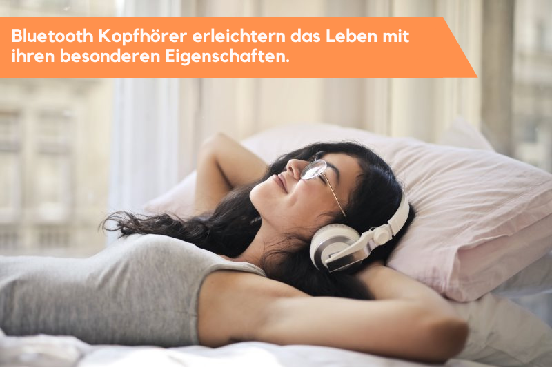 glückliches Mädchen liegt auf dem Bett und hat Bluetooth Kopfhörer auf.