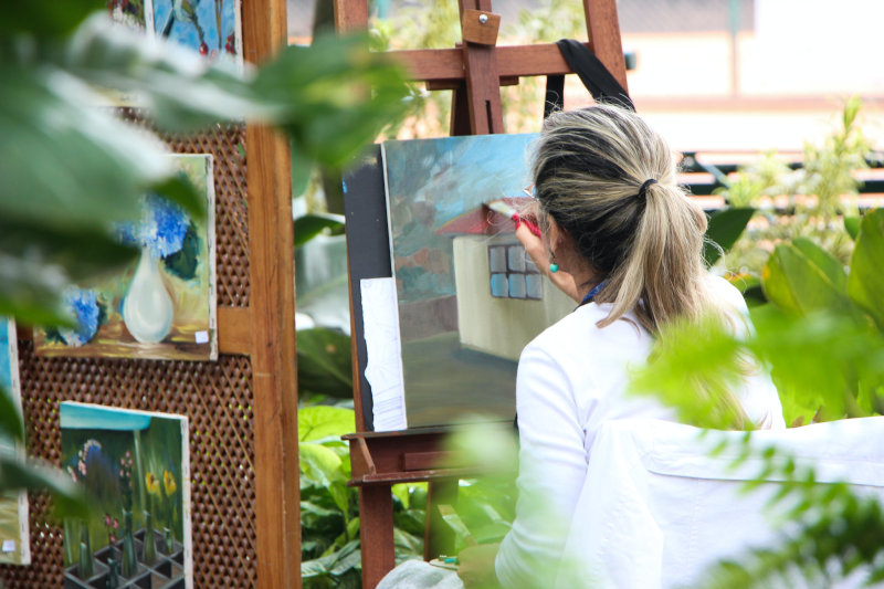 Frau malt mit Acrylfarben im Garten