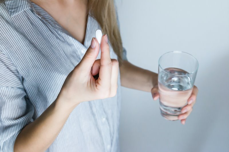 eine Frau hält eine Glas Wasser und eine Tablette in der Hand