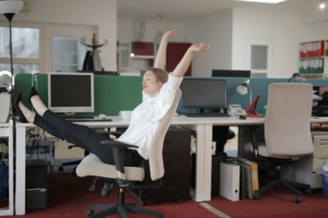 Eine Frau im Büro die sich auf einem Bürostuhl entspannt.