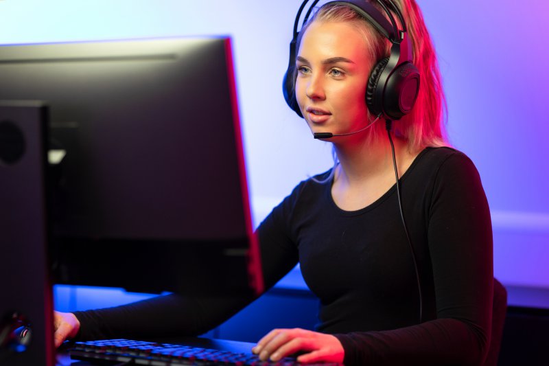 Junge Frau mit Headset sitzt an einem Gaming-Fernseher 