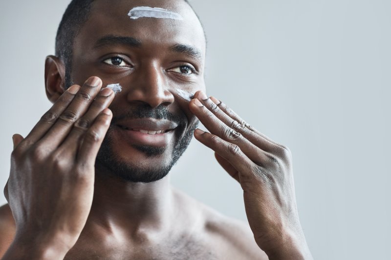Mann cremt sein Gesicht ein Mann trägt Creme auf sein Gesicht auf