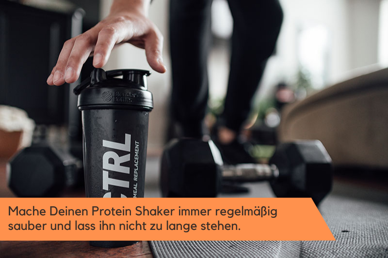 Person, die zuhause trainiert und nach dem Protein Shaker greift