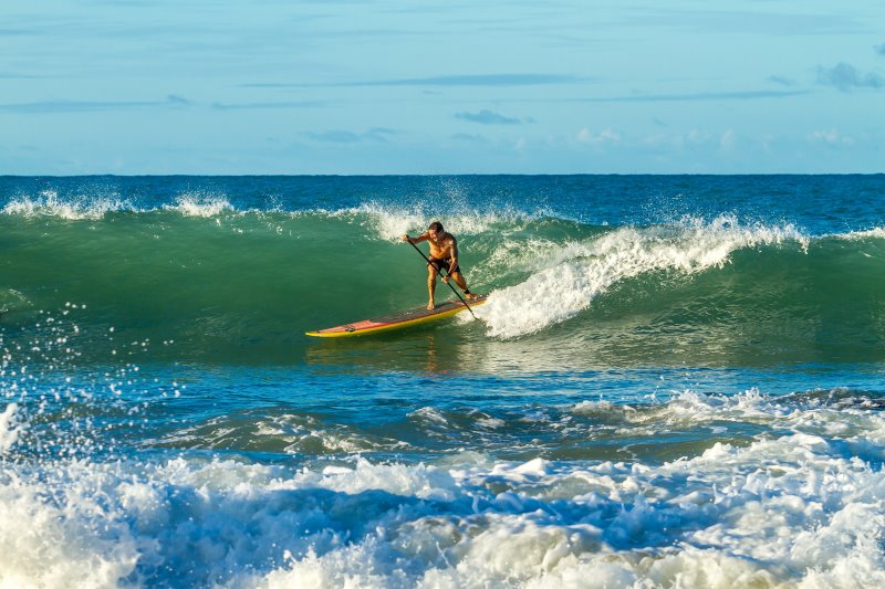Mann surft mit Wave-SUP