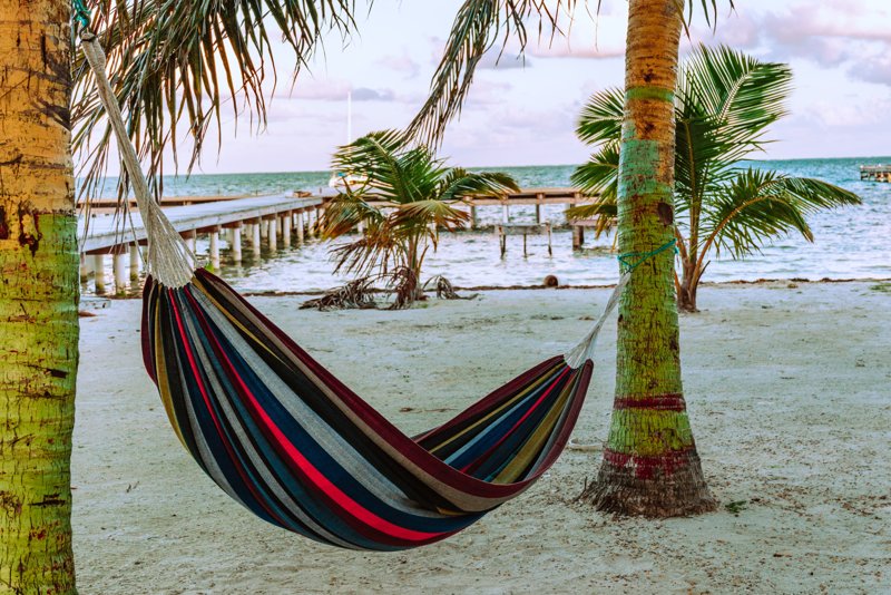 Tuchhängematte hängt an zwei Palmen am Strand