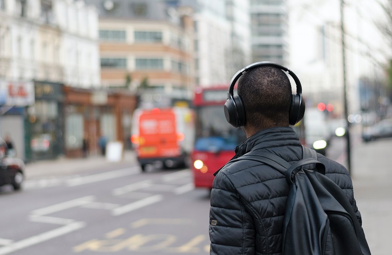 Eine Person mit Bluetooth over-ear Kopfhörern wartet auf den Bus