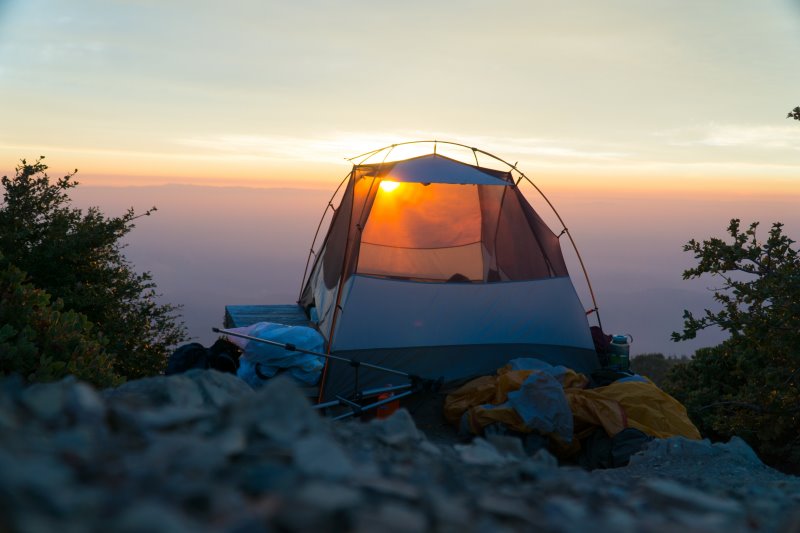 Einmannzelt auf einem Hügel bei Sonnenuntergang