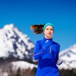 Frau mit Laufstirnband läuft in den Bergen