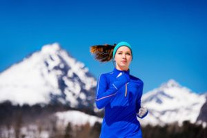 Frau mit Laufstirnband läuft in den Bergen