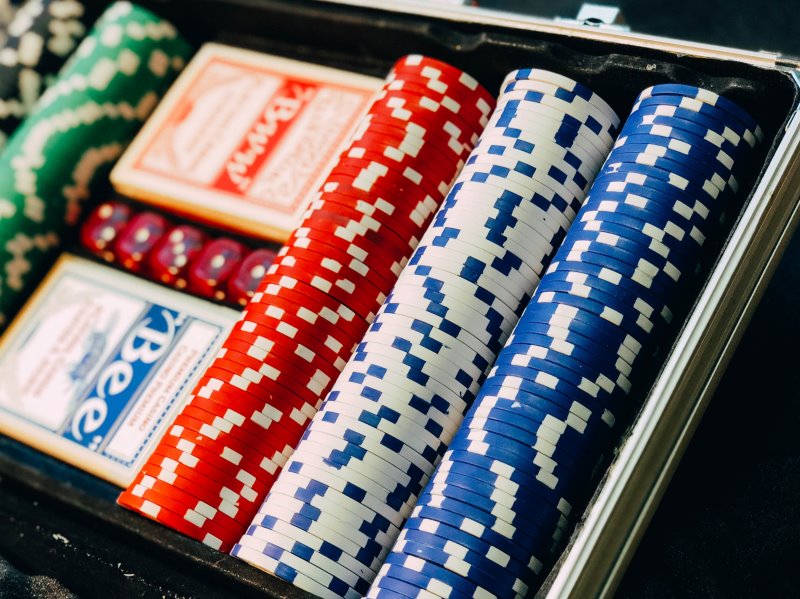 geöffneter Pokerkoffer mit Pokerchips, Kartendecks und Pokerwürfeln