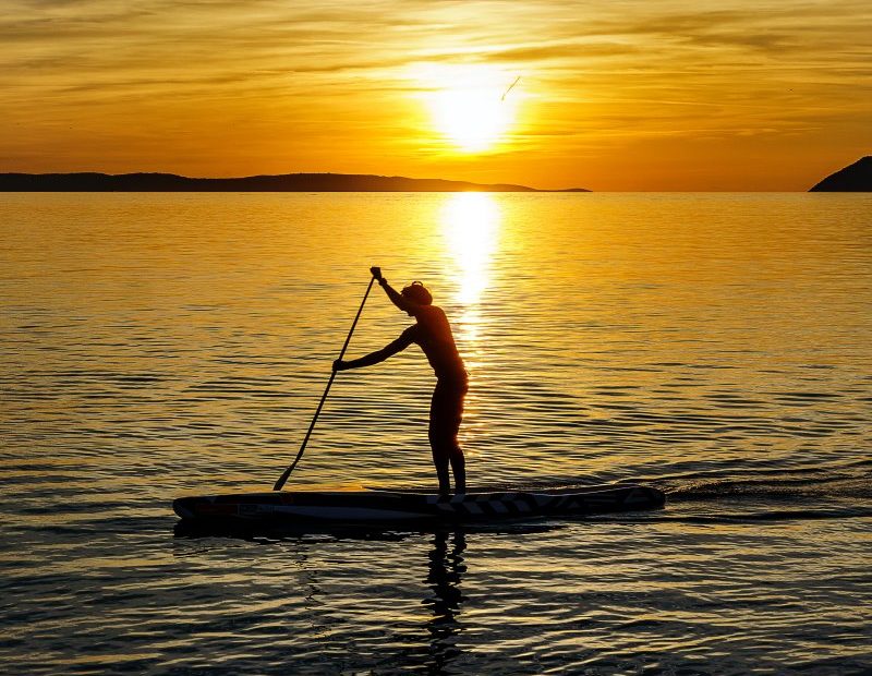 Ein Mann paddelt im Sonnenuntergang.