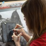 Eine Frau fertigt ein Bild eines Tieres mithilfe einer Airbrush-Pistole an