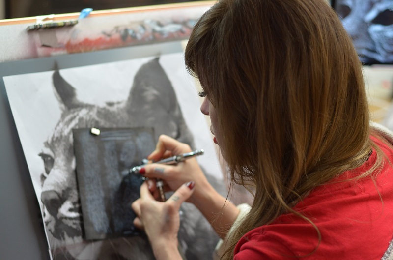 Eine Frau fertigt ein Bild eines Tieres mithilfe einer Airbrush-Pistole an