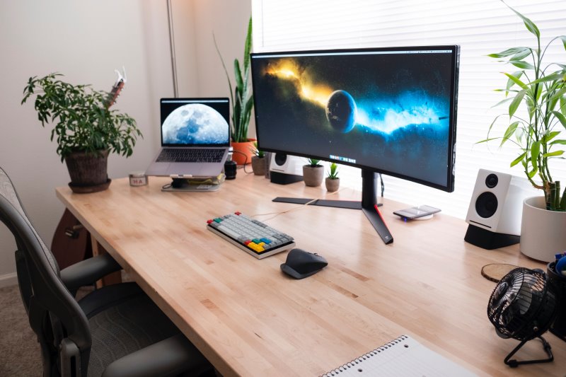 Curved Monitor und Laptop auf einem Schreibtisch