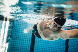 Männlicher Schwimmer mit Schwimmbrille im Hallenbad