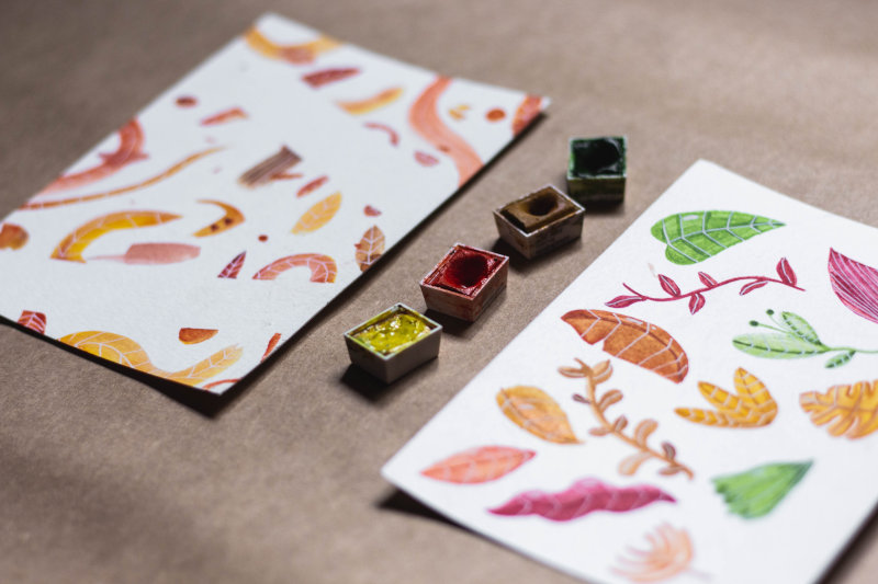 Aquarellpapier und Aquarellfarben Benutzte Aquarellfarben neben Aquarellbildern