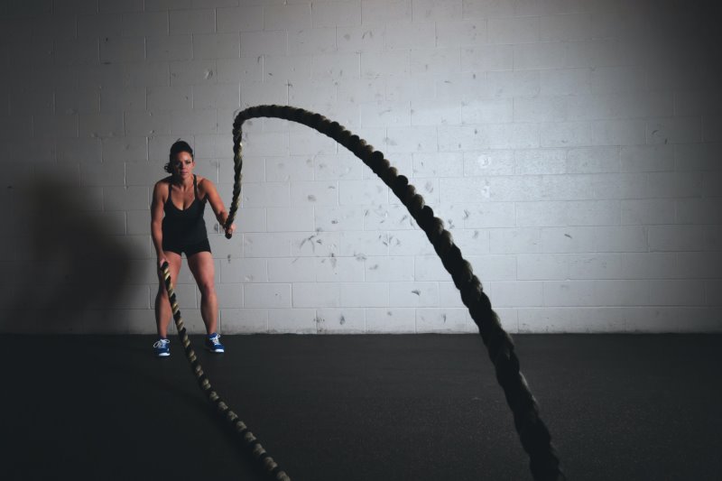 Frau trainiert entgegengesetzte Auf- und Abbewegung mit dem Battle Rope