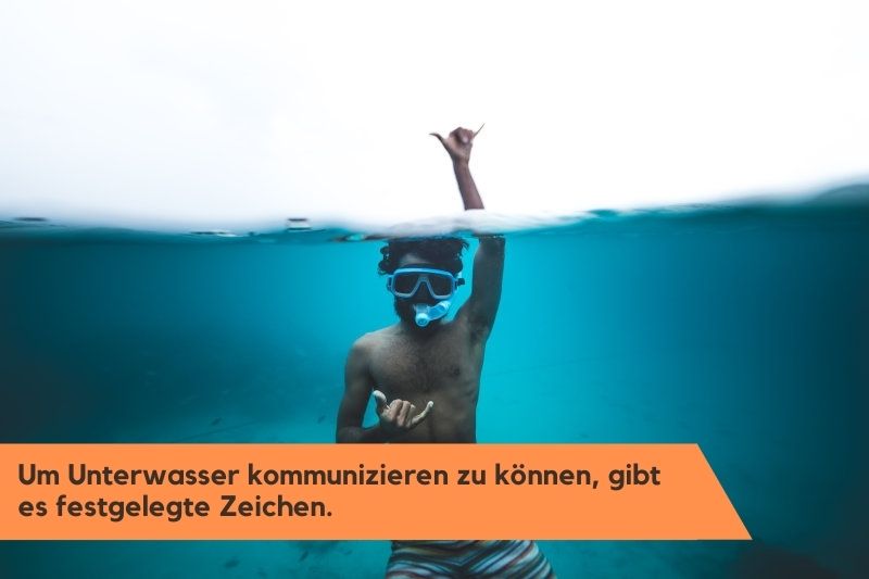 Mann schnorchelt und kommuniziert Unterwasser