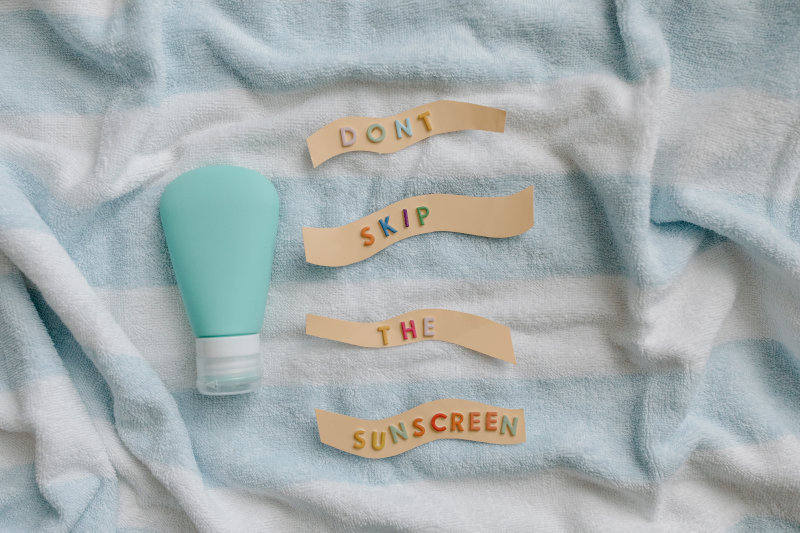 Sonnencreme trotz Strandschirm verwenden Eine Flasche mit Sonnencreme und der Schriftzug "Don't skip the sunscreen"