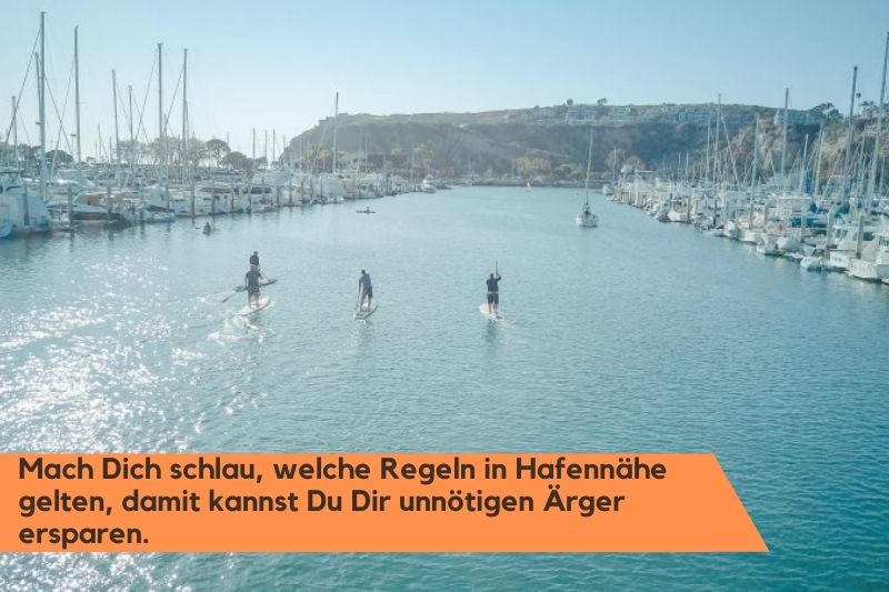 Mehrere Personen bei einem Hafen zum Stand-Up-Paddeling mit ihren SUP-Paddel.