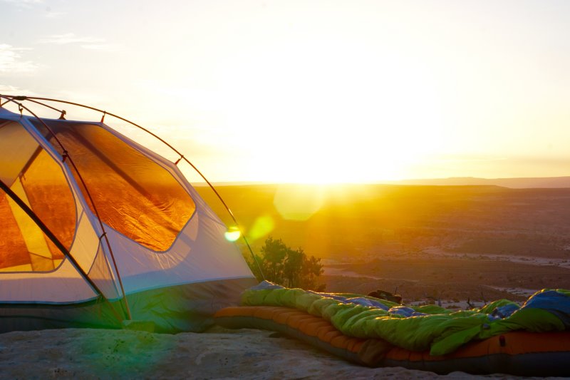 Campingbett und Zelt beim Sonnenaufgang